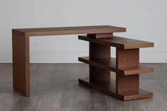 a wooden table sitting on top of a hard wood floor next to a white wall