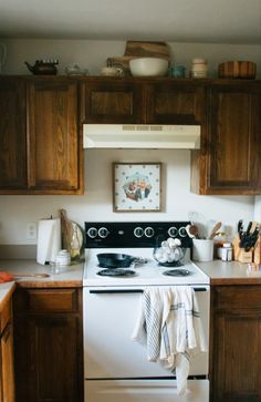 a white stove top oven sitting inside of a kitchen next to wooden cabinets and counter tops