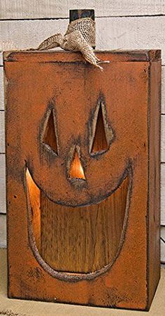 a wooden box with a carved pumpkin face on the front, and a bird sitting on top of it