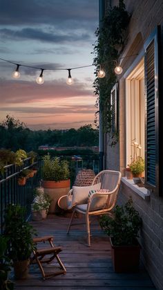 an outdoor patio with chairs and potted plants on the deck at night, lit by string lights