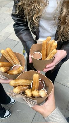 three people holding small boxes with donuts in them and dipping sauce on the top