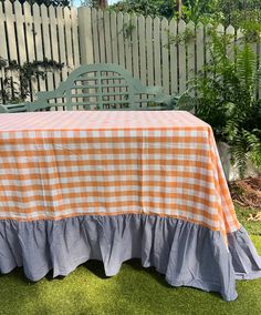 an orange and white checkered table cloth with ruffled edges on a green lawn