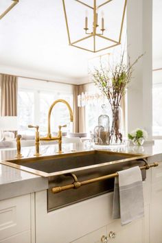 a kitchen sink under a chandelier in front of a window