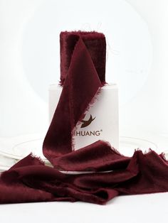 a piece of cloth sitting on top of a white plate next to a red napkin