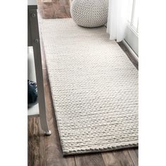 a large white rug on top of a wooden floor