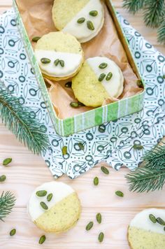 some cookies with frosting and pumpkin seeds in a green box on a wooden table