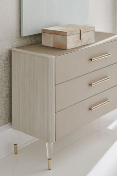 a white dresser with two drawers and a painting on the wall