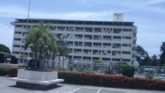 an empty parking lot in front of a large building with balconies and palm trees