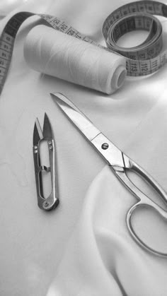 a pair of scissors, measuring tape and thread on a white cloth