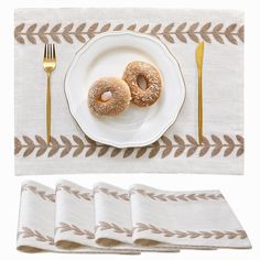 two donuts are on a plate next to forks and napkins with gold trim