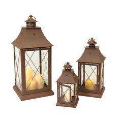 three brown lanterns with lit candles in them