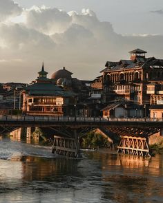 a bridge over a body of water with buildings on the other side and clouds in the sky