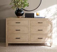 a wooden dresser sitting in front of a wall with a plant on top of it