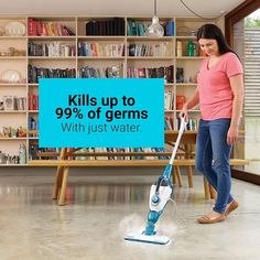 a woman using a steam mop to clean the floor in front of bookshelves