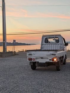 the truck is parked on the gravel by the water