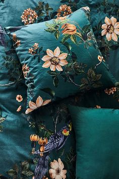 the comforter is made up with many flowers and birds on it, along with two matching pillows