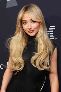 a woman with long blonde hair and blue eyes wearing a black dress at an event