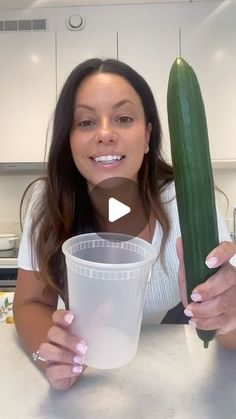 a woman holding a cucumber and a plastic cup