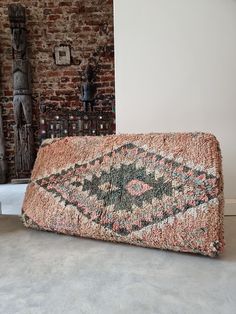 an old rug on the floor in front of a brick wall