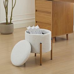 a wooden desk with a white round storage container on it and a potted plant next to it