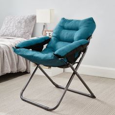 a blue folding chair sitting on top of a carpeted floor next to a bed