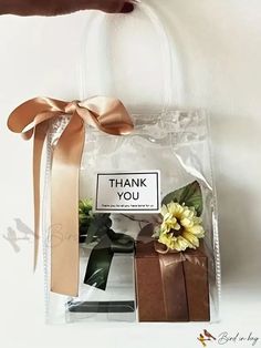 a person holding a clear bag with flowers in it and a thank you sign on the front