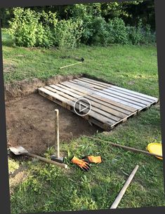 a wooden pallet laying in the middle of a field with gardening tools on it