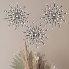 a vase filled with flowers next to two metal wall hangings in the shape of snowflakes