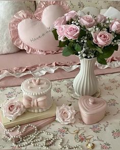 pink roses in a white vase on a table with other items and decorations around it