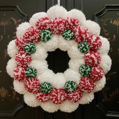 a christmas wreath hanging on a door with pom - poms and candy canes