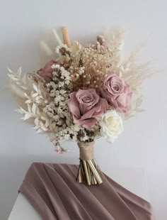 a bouquet of flowers sitting on top of a white table next to a purple cloth