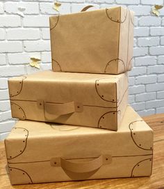 two brown boxes sitting on top of a wooden table next to a white brick wall