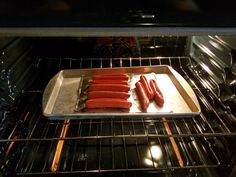 hot dogs cooking in an oven on a tray