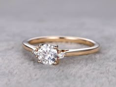 an engagement ring with three stones on the side and a diamond in the middle, sitting on a gray surface