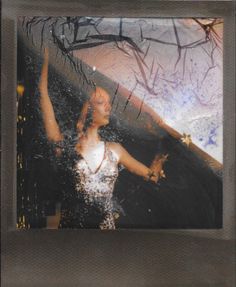 a polaroid photograph of a woman dancing in the rain with her arms raised up