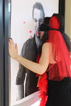 a woman dressed in red and black standing next to a man with his face painted on