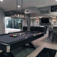 a pool table in the middle of a room with lights hanging from it's ceiling