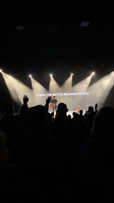 people are standing on stage with their hands in the air as they sing to someone