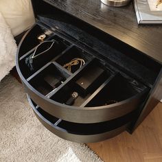 an open drawer in the middle of a coffee table with jewelry inside and on it