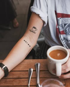 a person sitting at a table with a cup of coffee and spoons in front of them