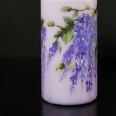 a white candle with purple flowers painted on it