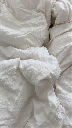 an unmade bed with white sheets and pillows