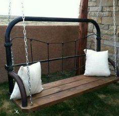 a porch swing made from a headboard with two white pillows on it and one black iron frame