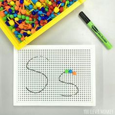 the letter s is made out of plastic beads and crayons with a marker