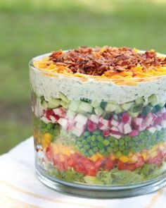 a layered salad in a glass dish on top of a table