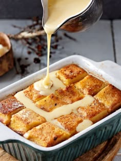 a pan filled with bread and cheese being drizzled on top of it