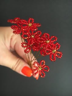 a woman's hand holding red beaded flowers