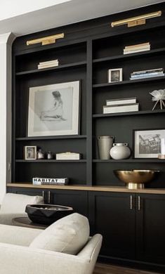 a living room with black bookcases and white couches in front of it