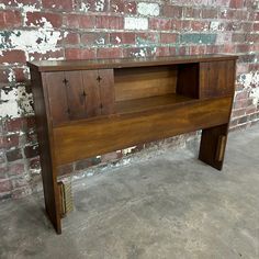 a wooden bench sitting in front of a brick wall