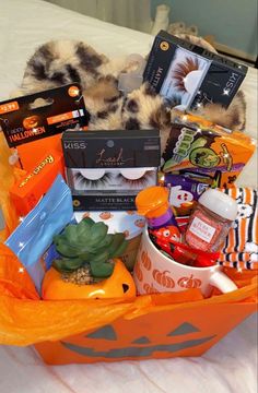 an orange basket filled with halloween items on top of a bed